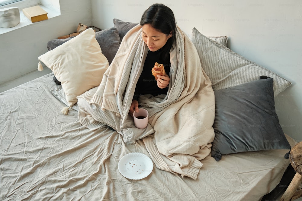 a woman sitting on a bed with a blanket over her head
