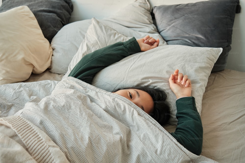 una donna sdraiata a letto sotto una coperta