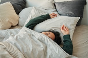 a woman laying in bed under a blanket