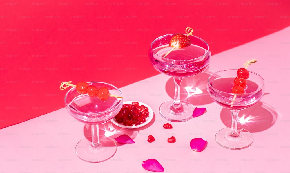 três taças de vinho com cerejas sobre uma mesa