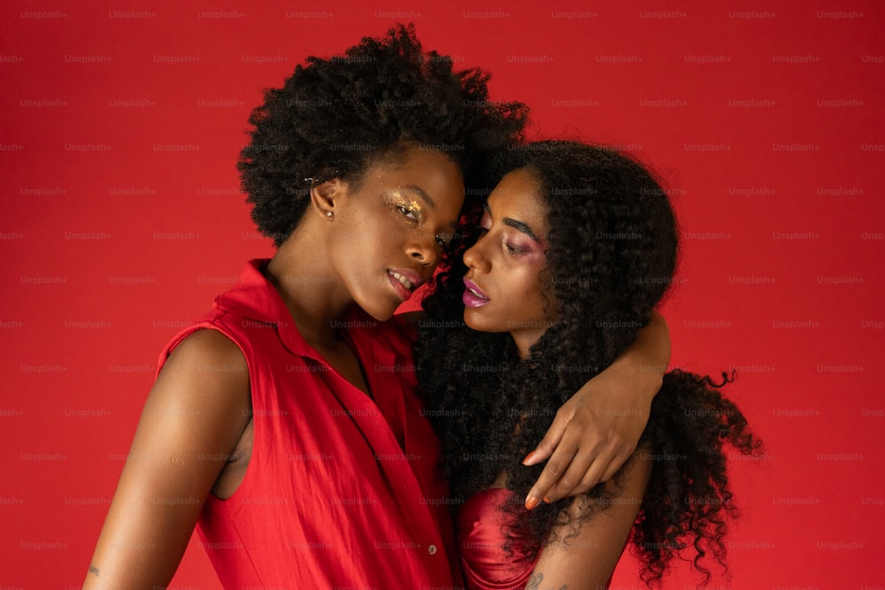 two young women embracing each other on a red background