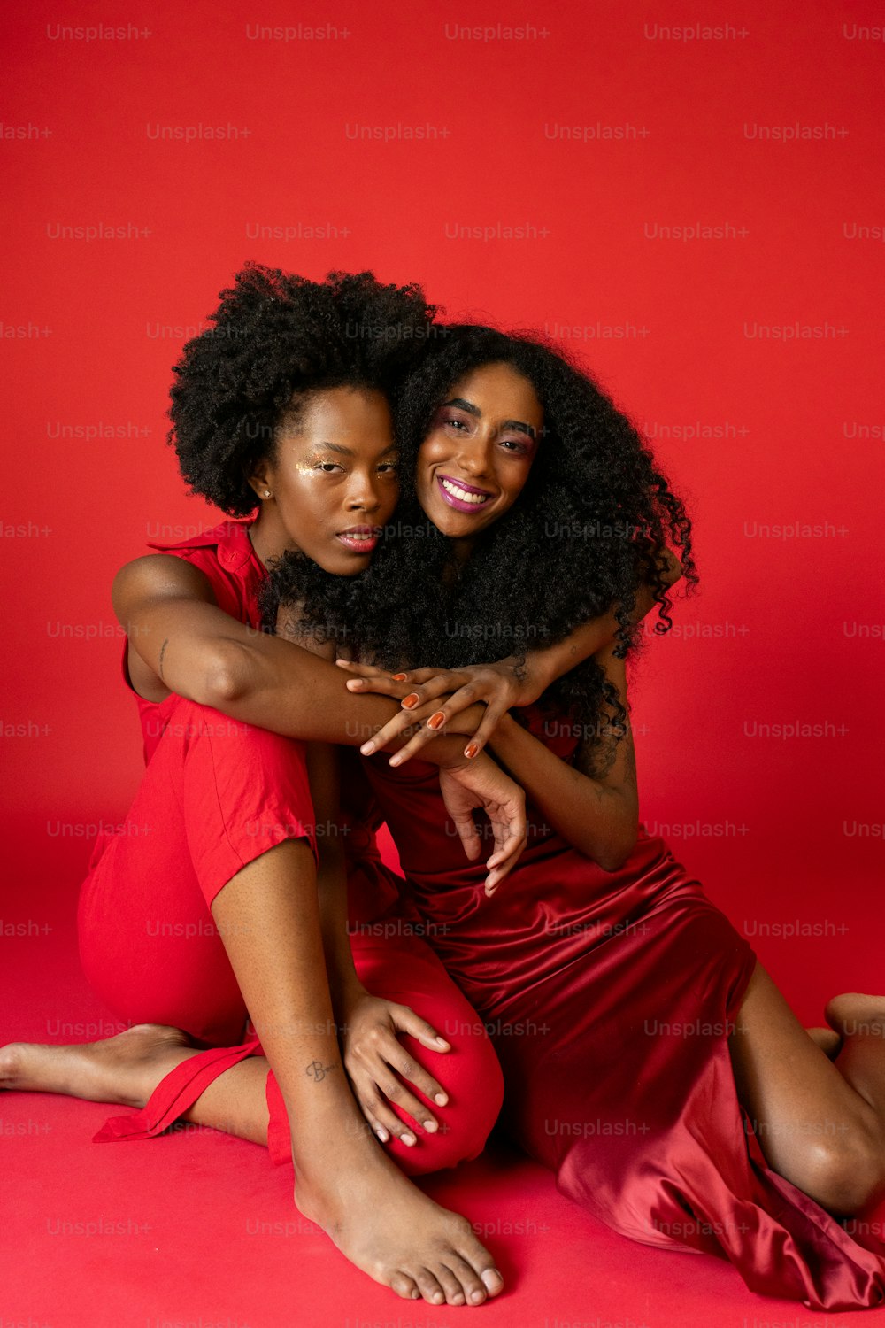 two women sitting on the ground hugging each other