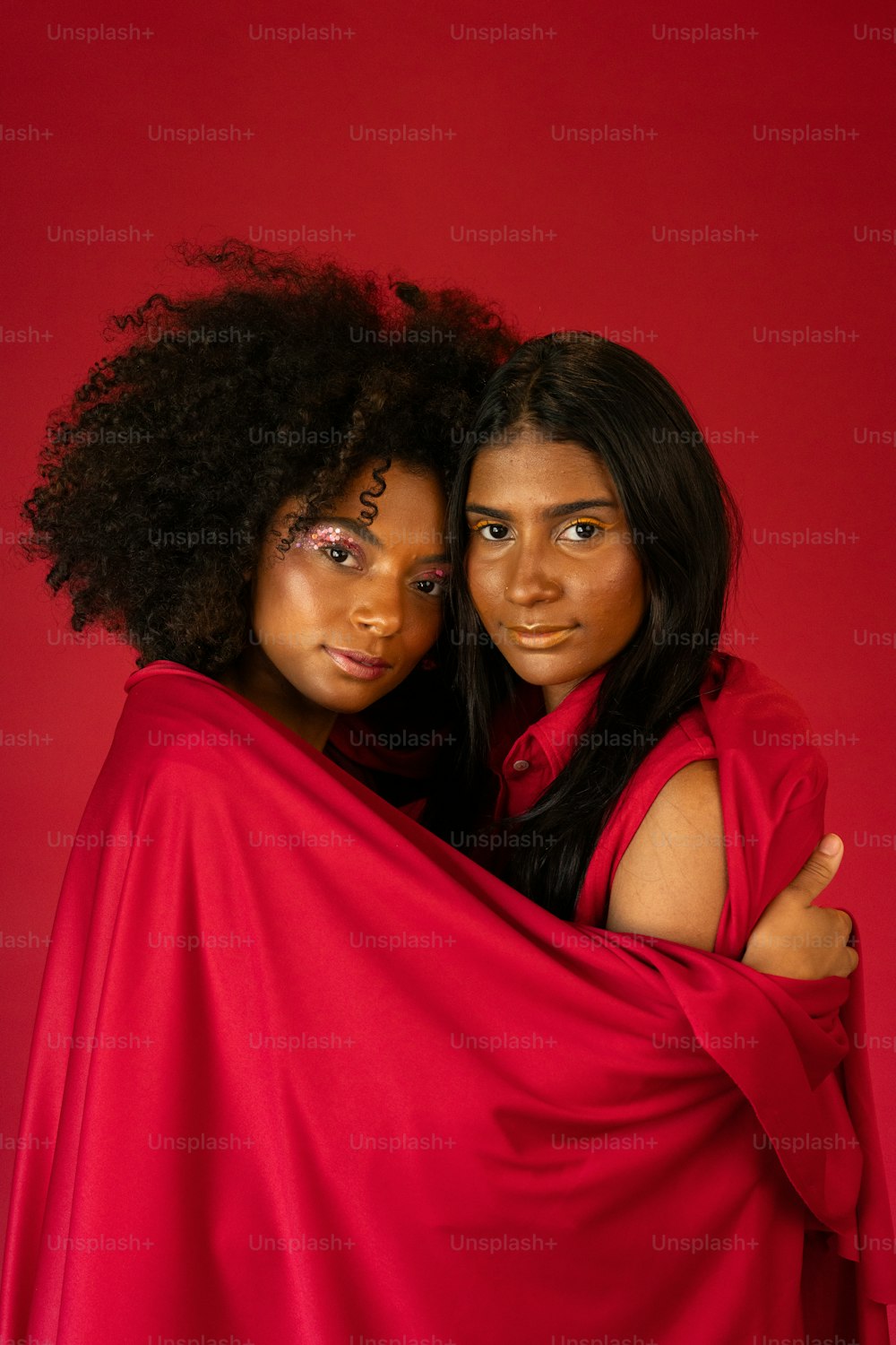 Zwei Frauen, die in ein rotes Tuch gehüllt für ein Foto posieren