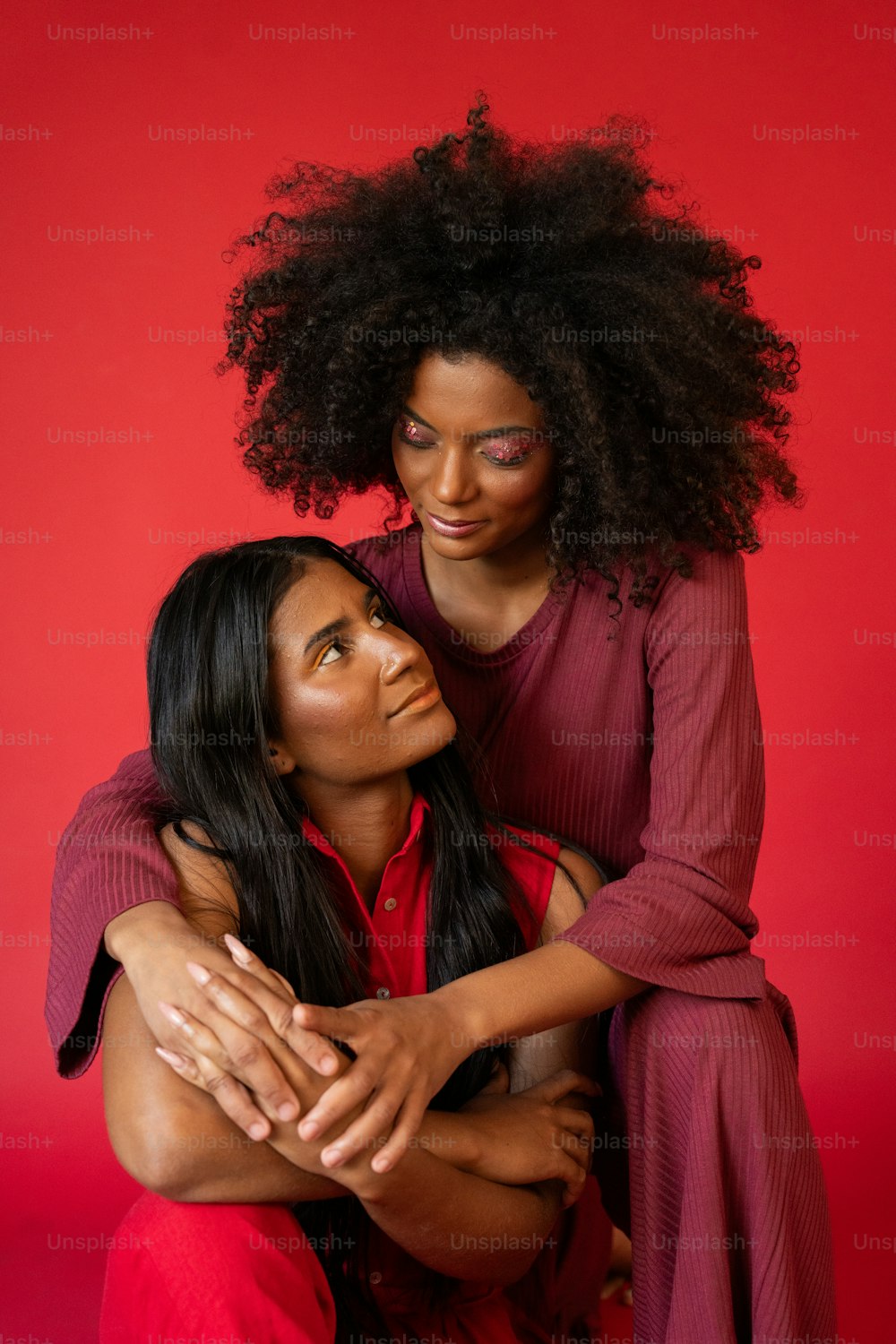 zwei Frauen, die sich auf rotem Hintergrund umarmen