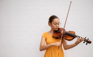 a woman in a yellow dress playing a violin