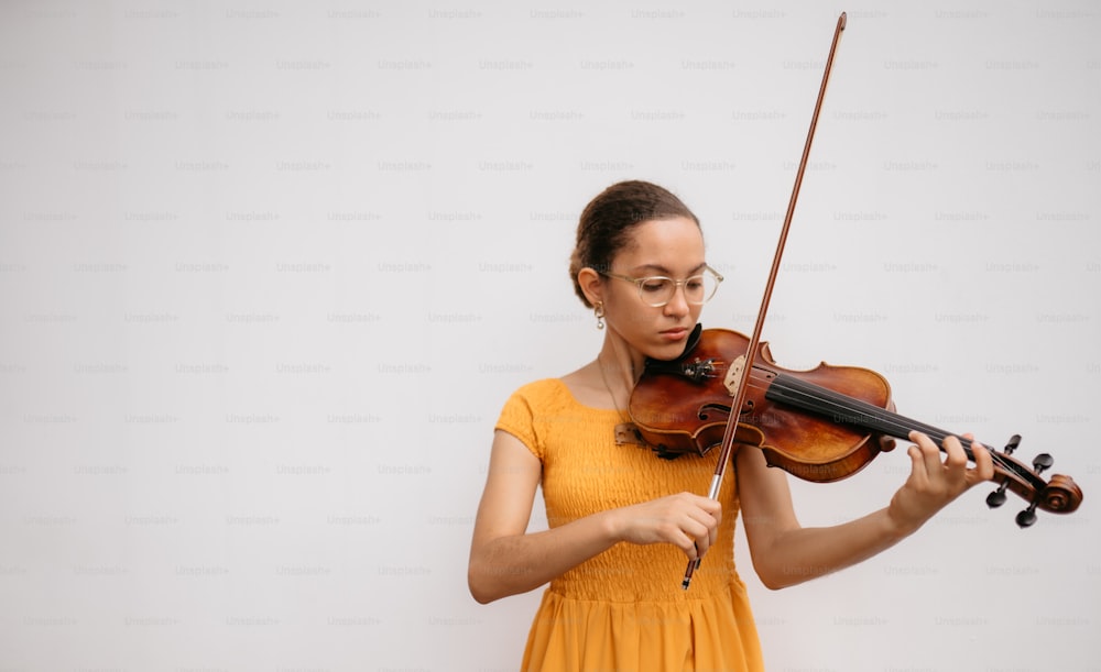 a woman in a yellow dress playing a violin