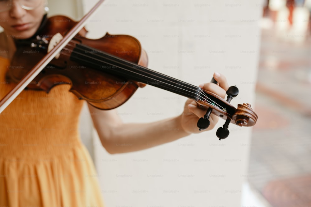 a woman in a yellow dress playing a violin