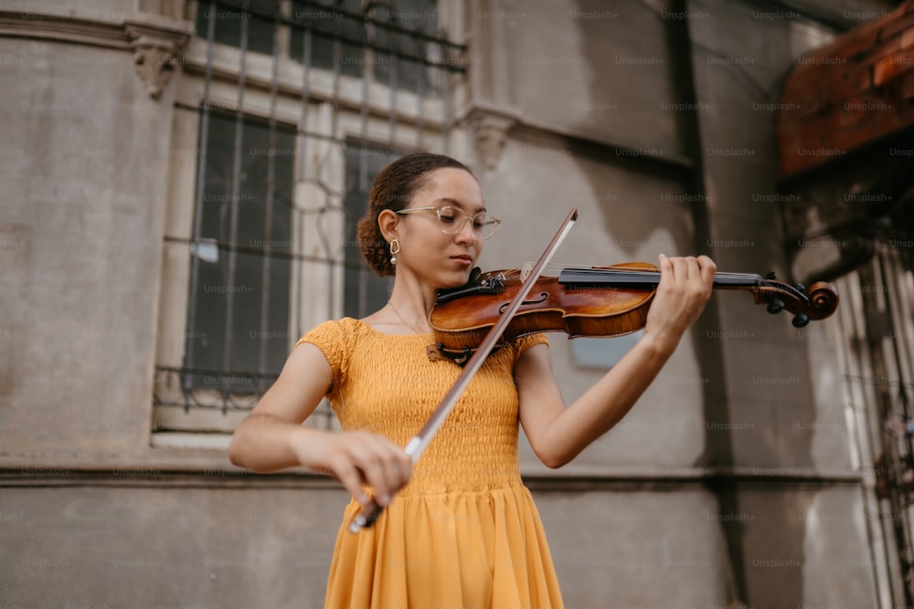a woman in a yellow dress playing a violin