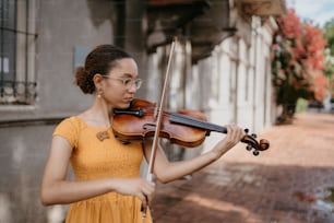 a woman in a yellow dress playing a violin