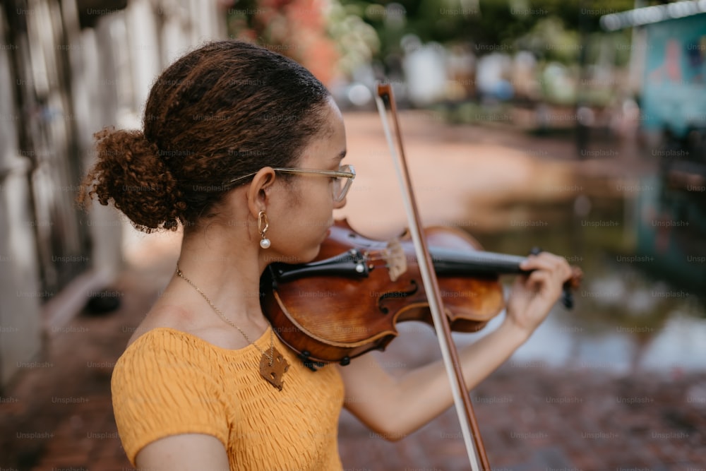 una mujer con una blusa amarilla tocando un violín