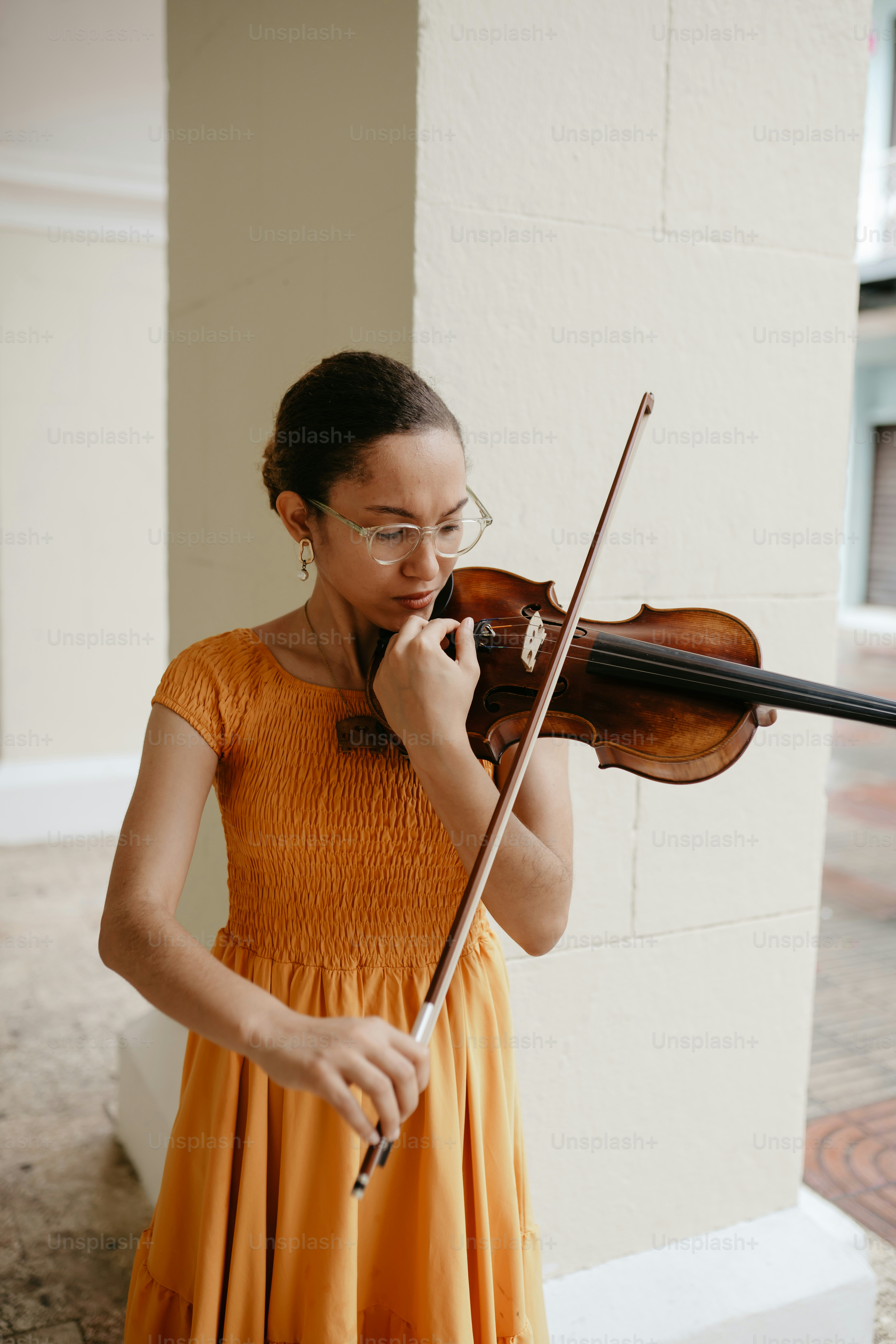 una mujer con un vestido naranja tocando un violín