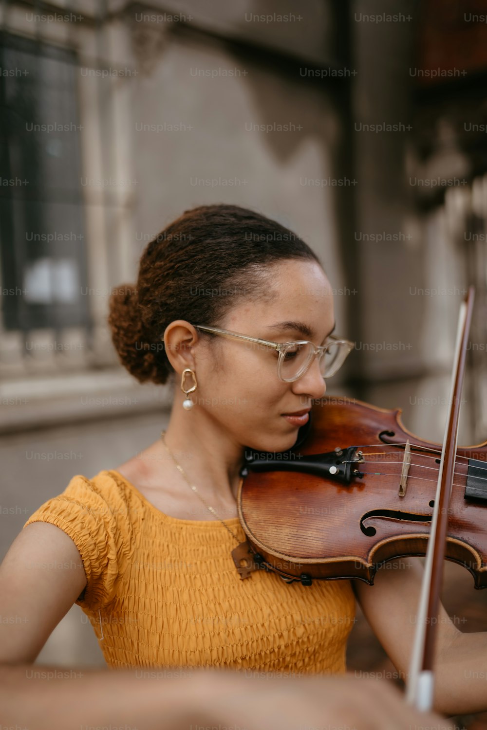 a woman in a yellow shirt playing a violin
