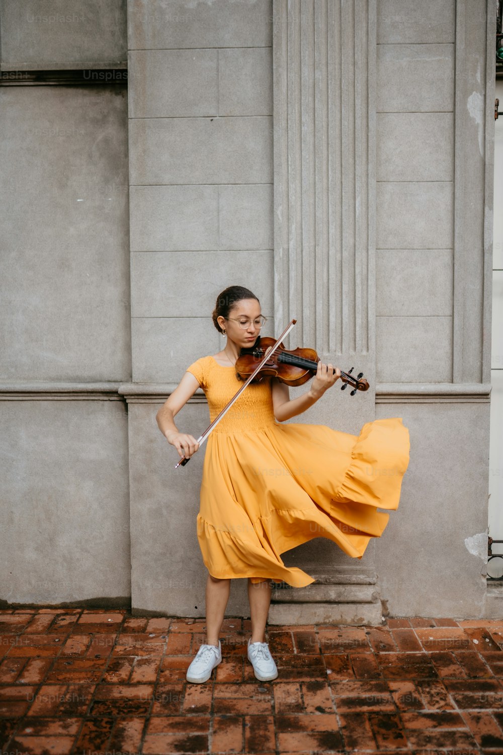 노란색 드레스를 입은 여성이 바이올린을 연주하고 있다