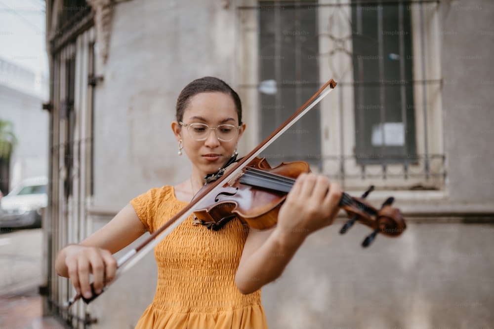 uma mulher em um vestido amarelo tocando um violino