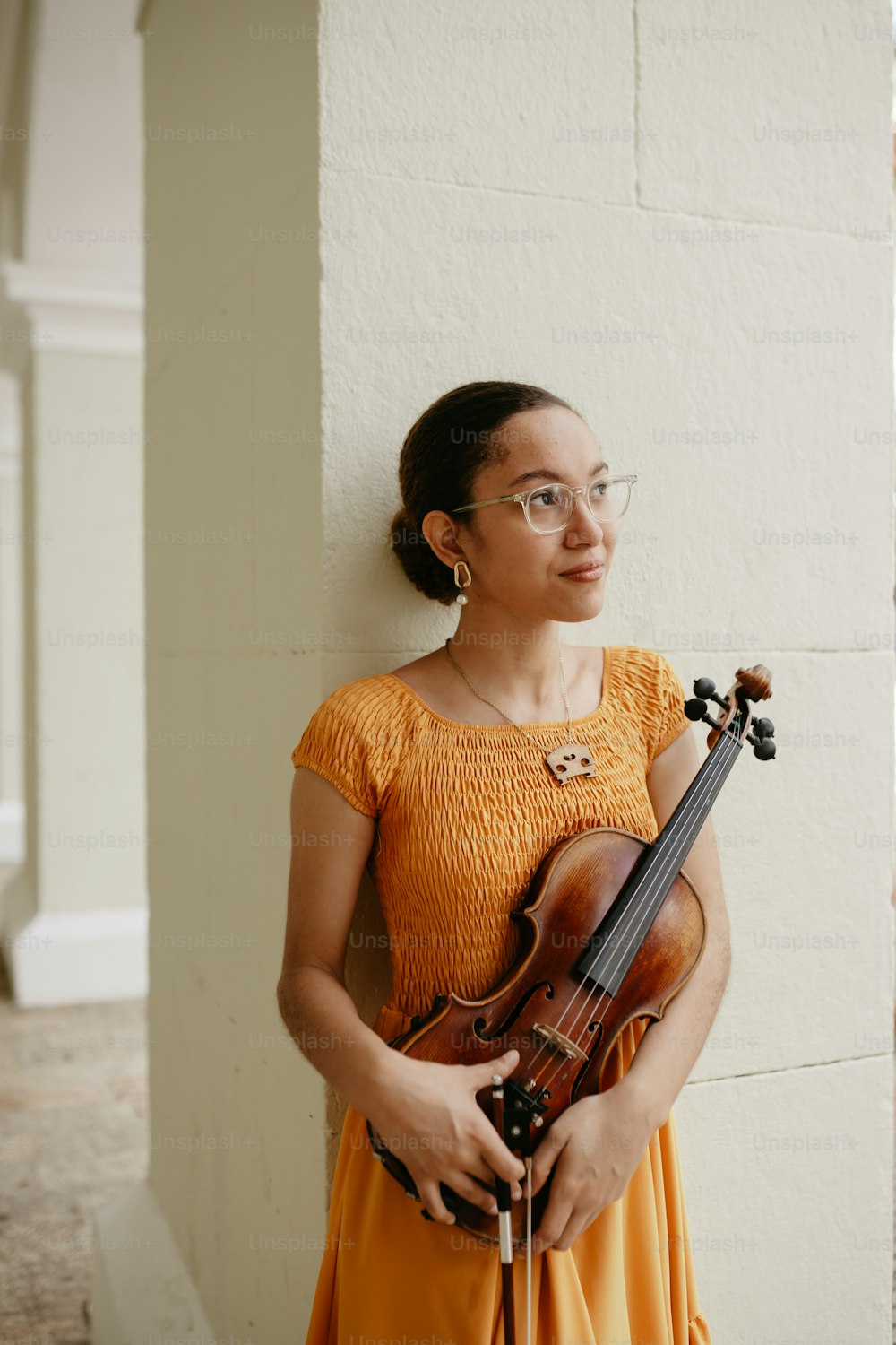 una mujer con un vestido amarillo sosteniendo un violín