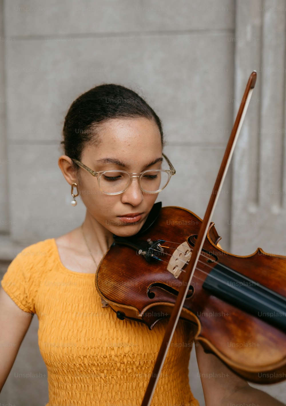 a woman in a yellow shirt holding a violin