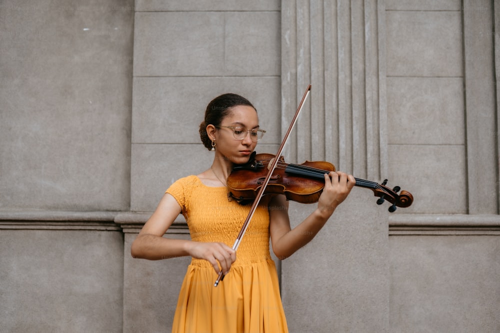 uma mulher em um vestido amarelo tocando um violino