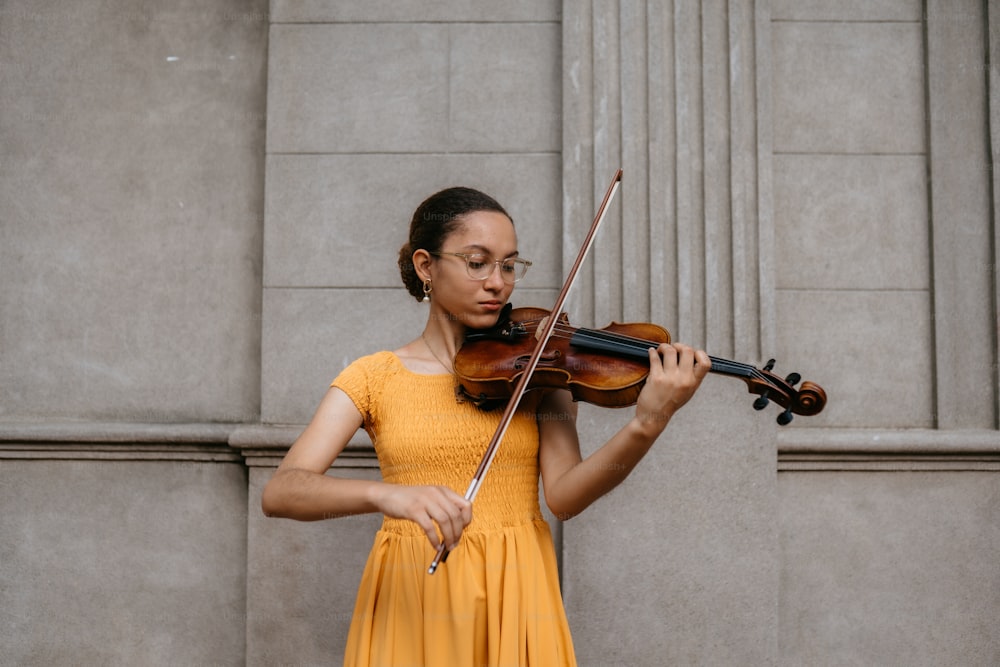 a woman in a yellow dress playing a violin