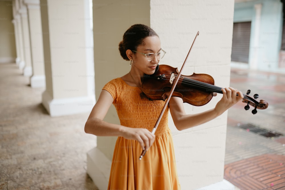 uma mulher em um vestido laranja tocando um violino