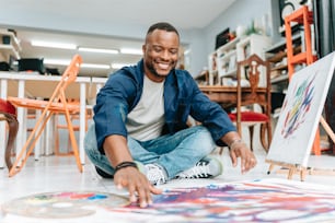 a man sitting on the floor in front of a painting