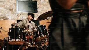 a man playing drums in front of a stone wall