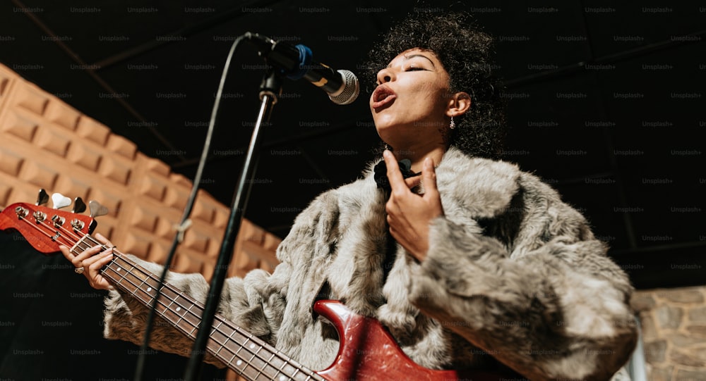 a woman singing into a microphone while holding a bass