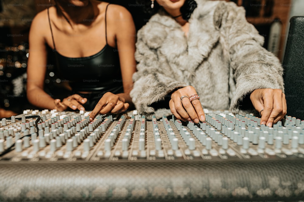 two women sitting at a sound board in a recording studio