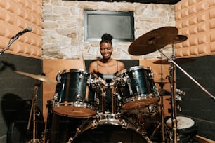 a woman sitting behind a drum set in a recording studio