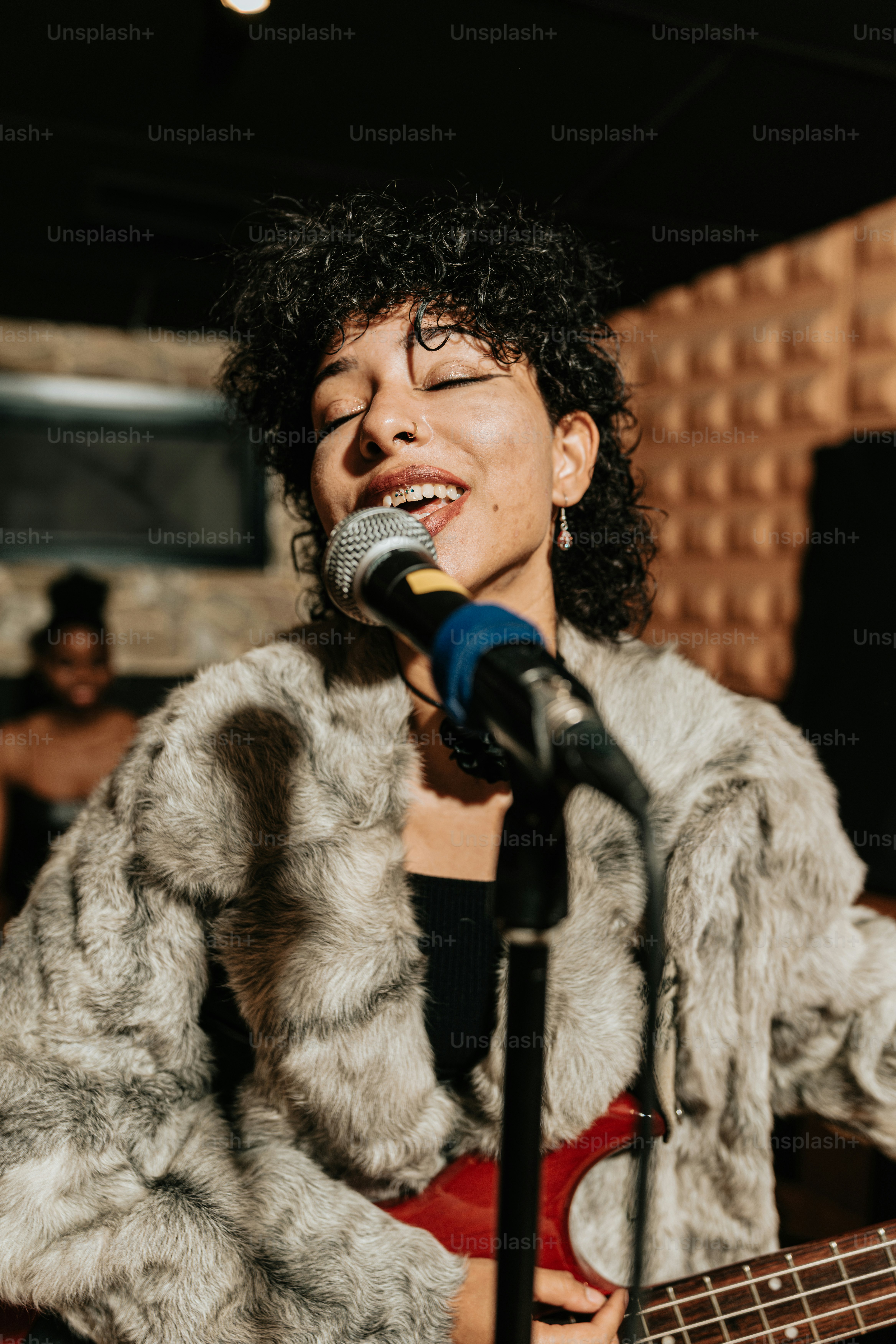a woman singing into a microphone while holding a bass