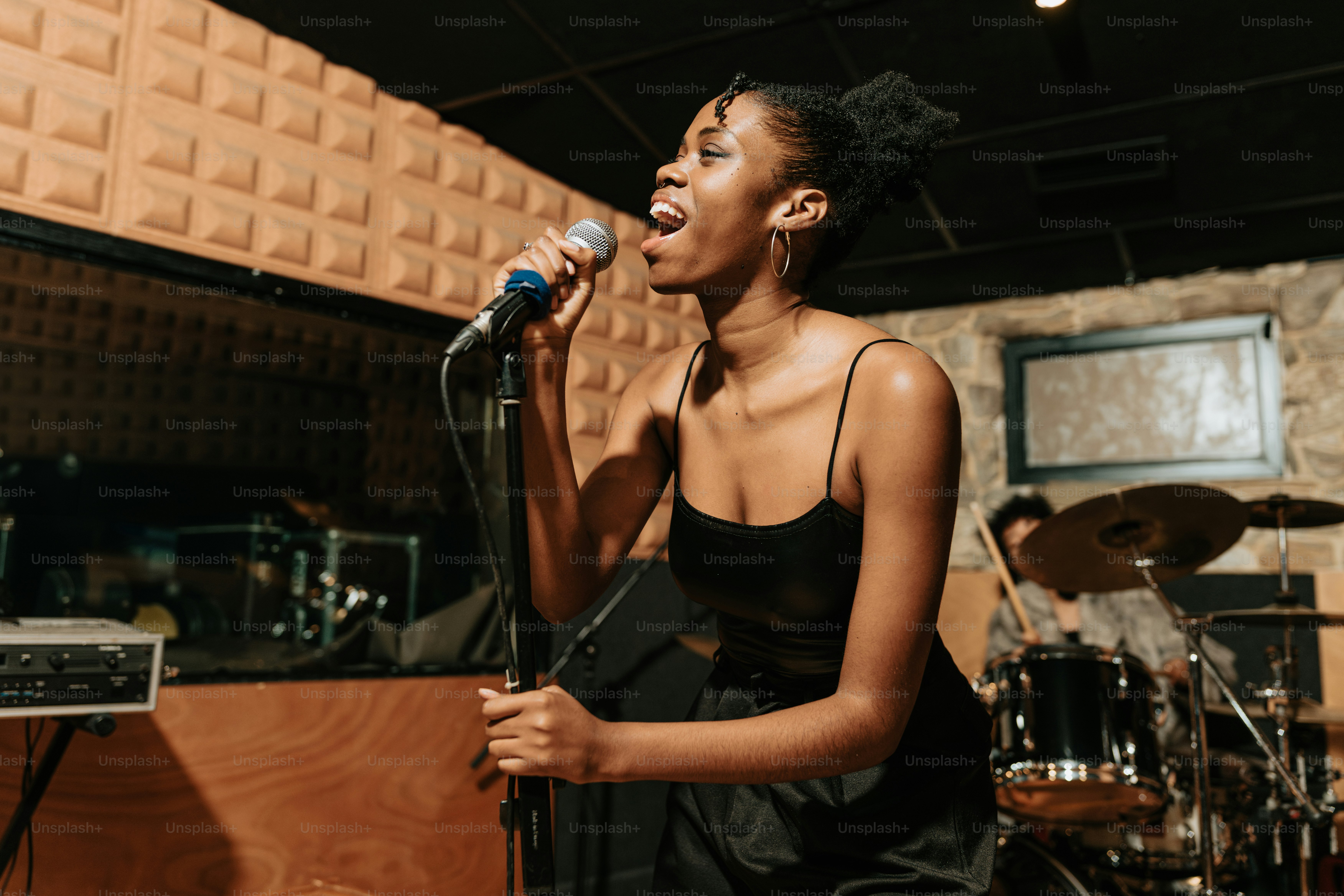 a woman singing into a microphone in a recording studio