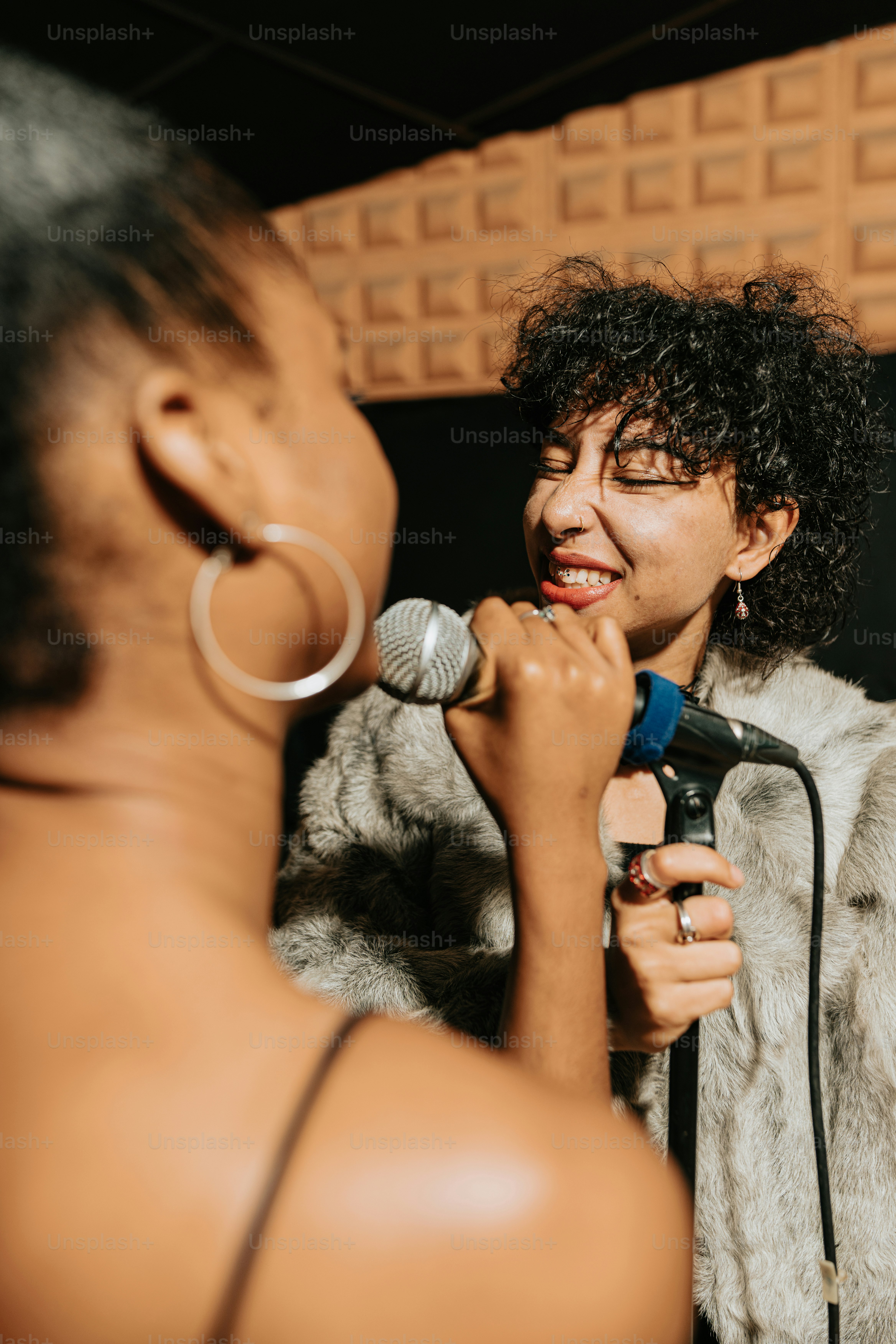 a woman holding a microphone while standing next to another woman