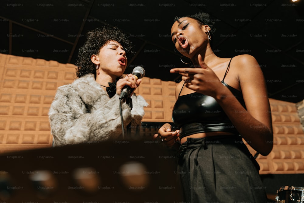 two women standing next to each other in front of a microphone