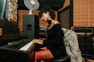 a woman sitting at a piano in a recording studio