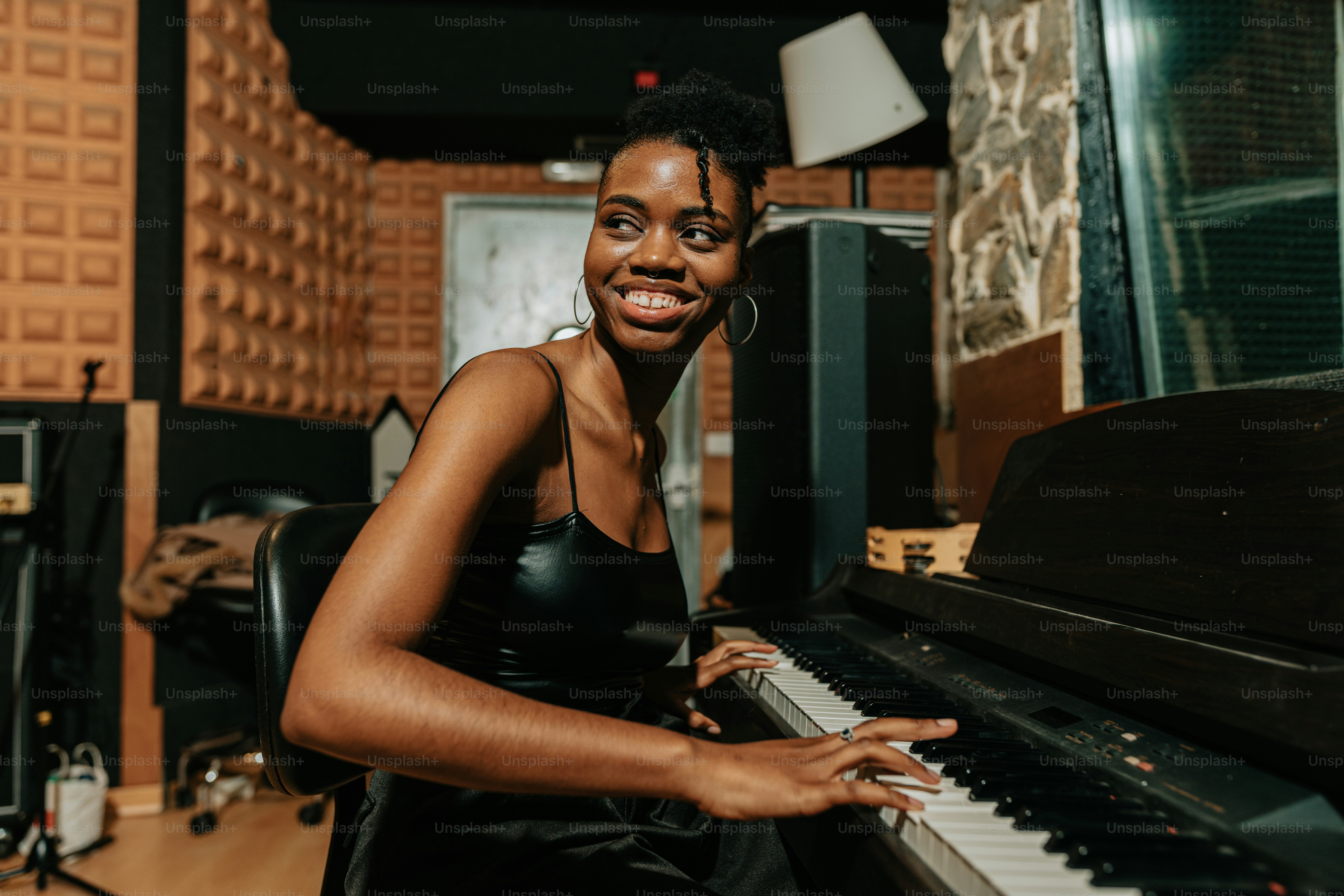 a woman sitting at a piano in a recording studio