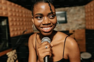 a smiling woman holding a microphone in a recording studio