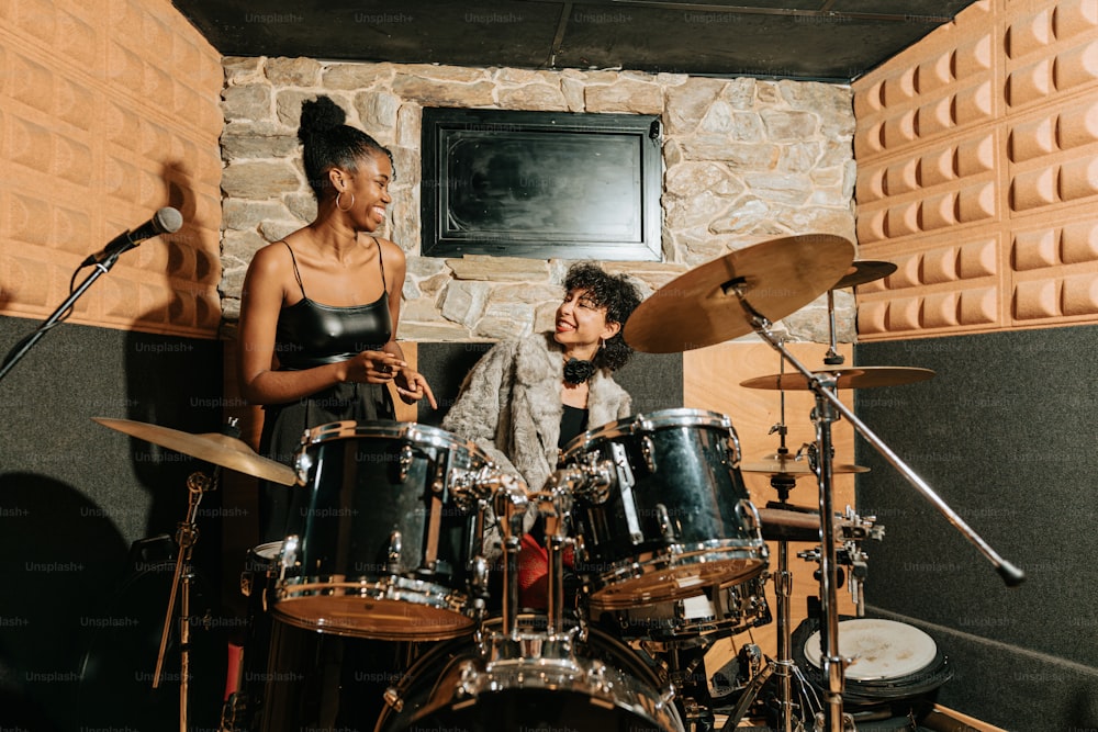 un homme et une femme jouant de la batterie dans un studio d’enregistrement