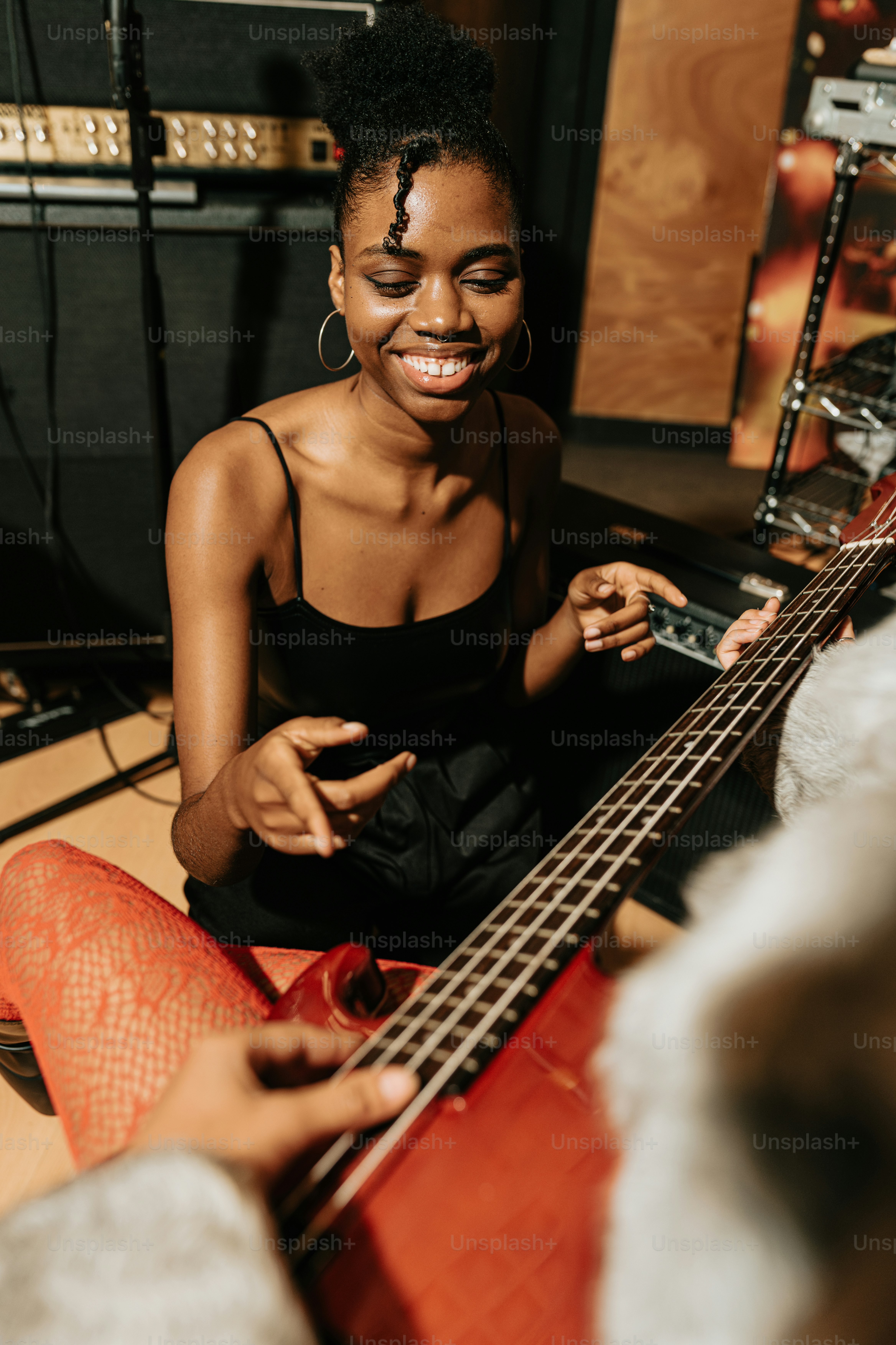 a woman sitting on the floor playing a bass