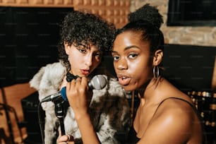 two young women are singing into a microphone