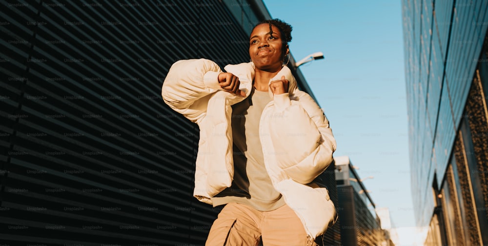 a man in a white jacket and tan pants walking down a street