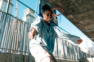 a woman is playing basketball under a bridge