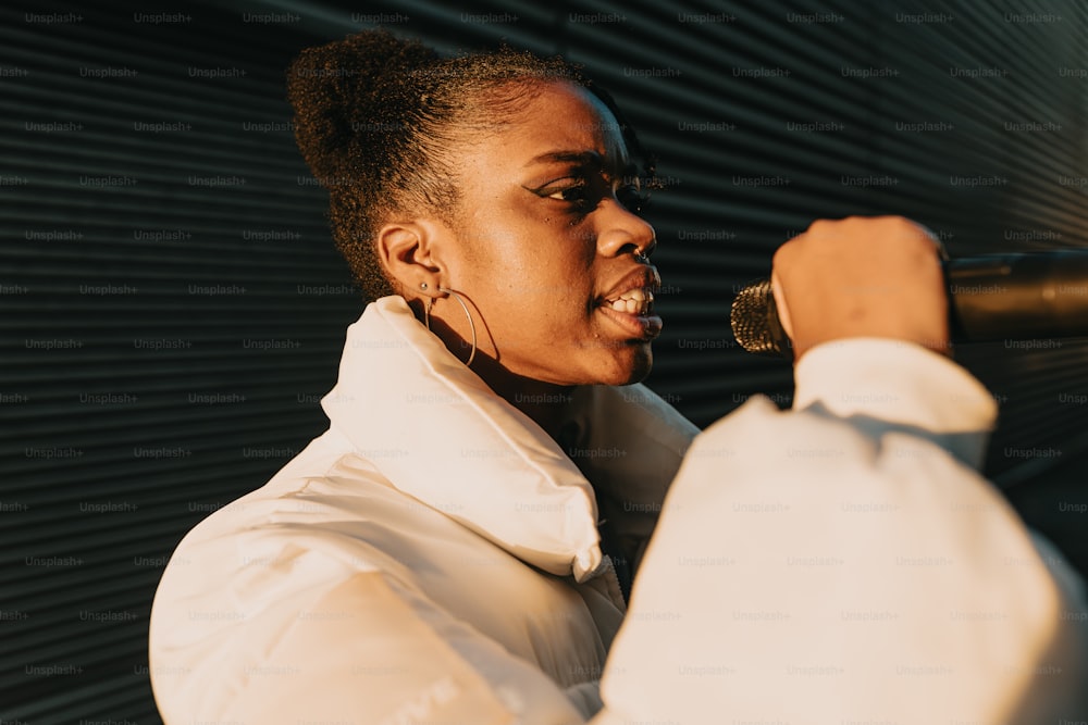 a woman singing into a microphone in front of a wall