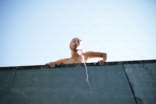 a woman with a shaved head standing on a ledge