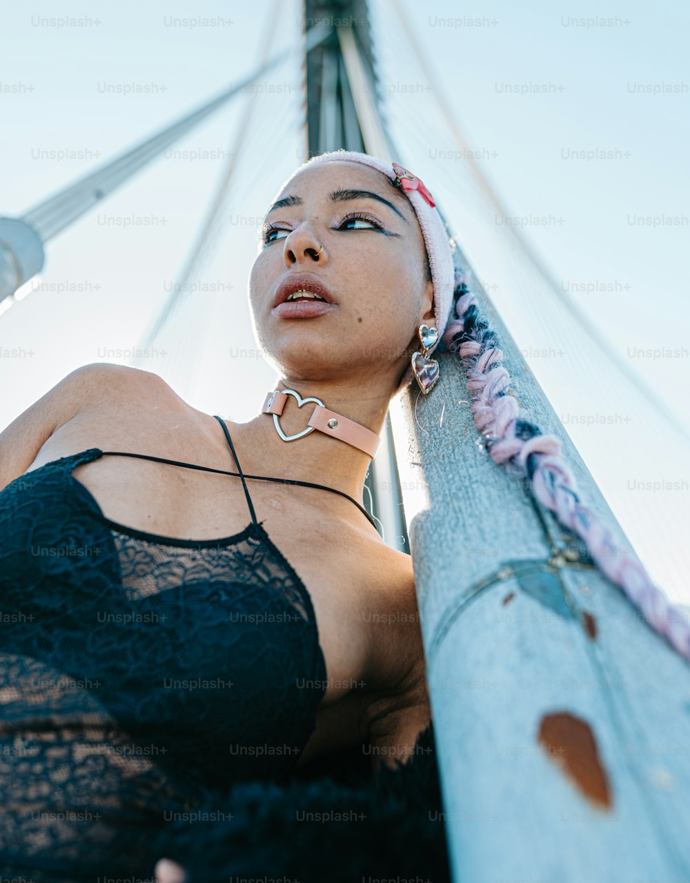 a woman in a black bra top leaning against a pole