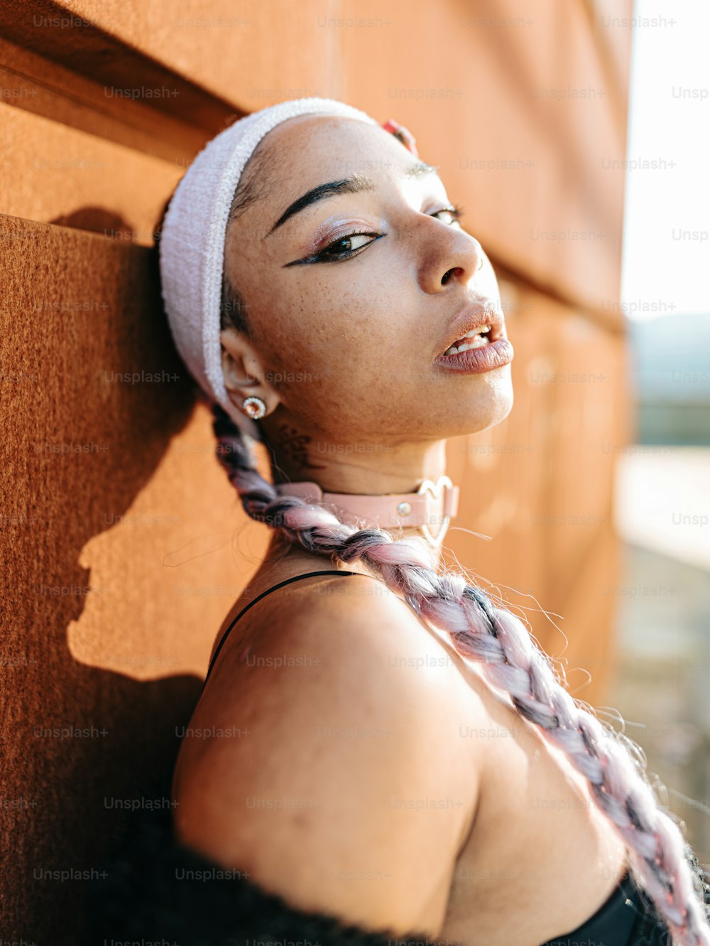 a woman leaning against a wall wearing a headband