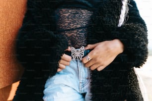 a woman wearing a black jacket and a butterfly ring