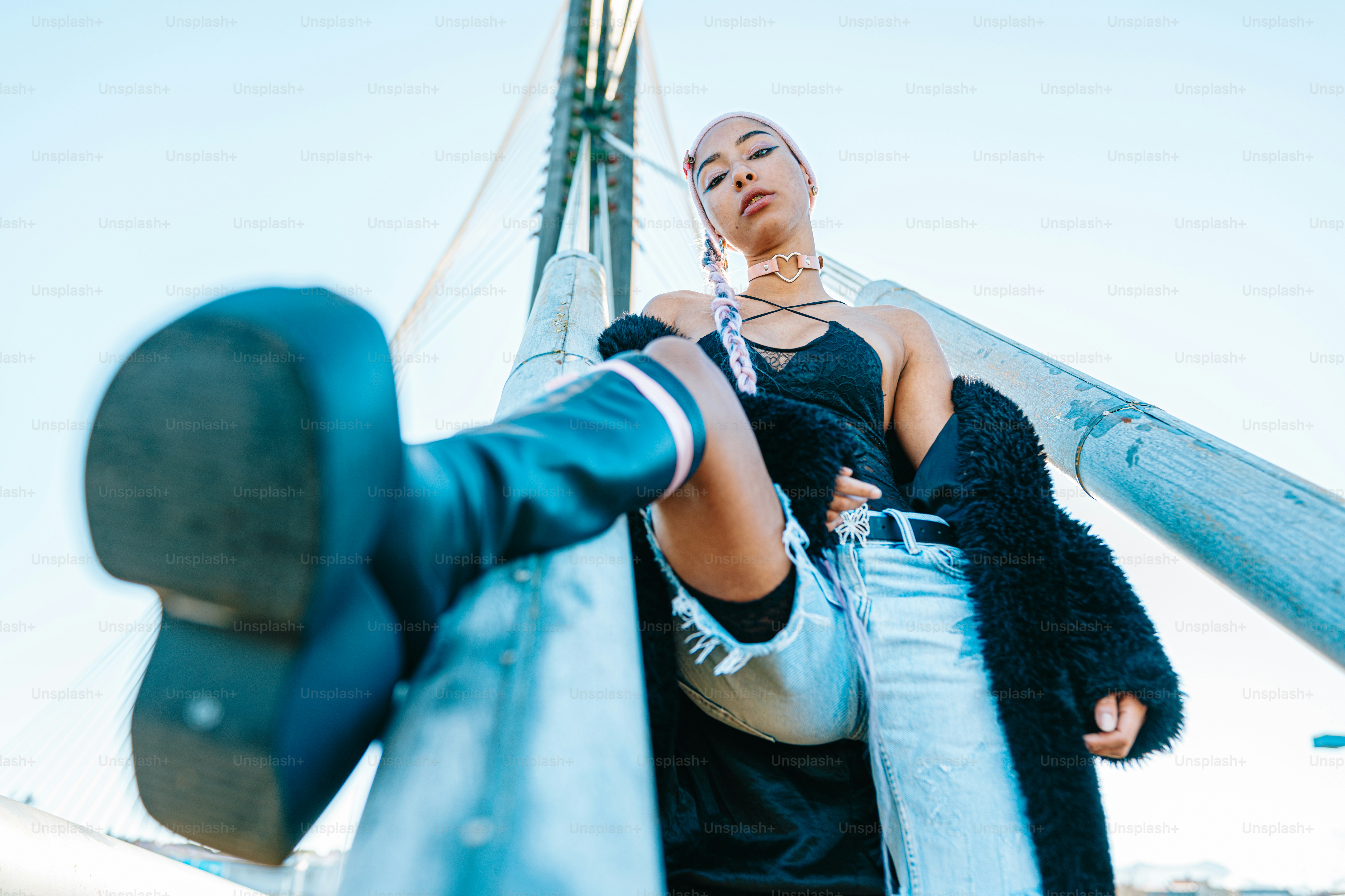 a woman is leaning against a metal pole