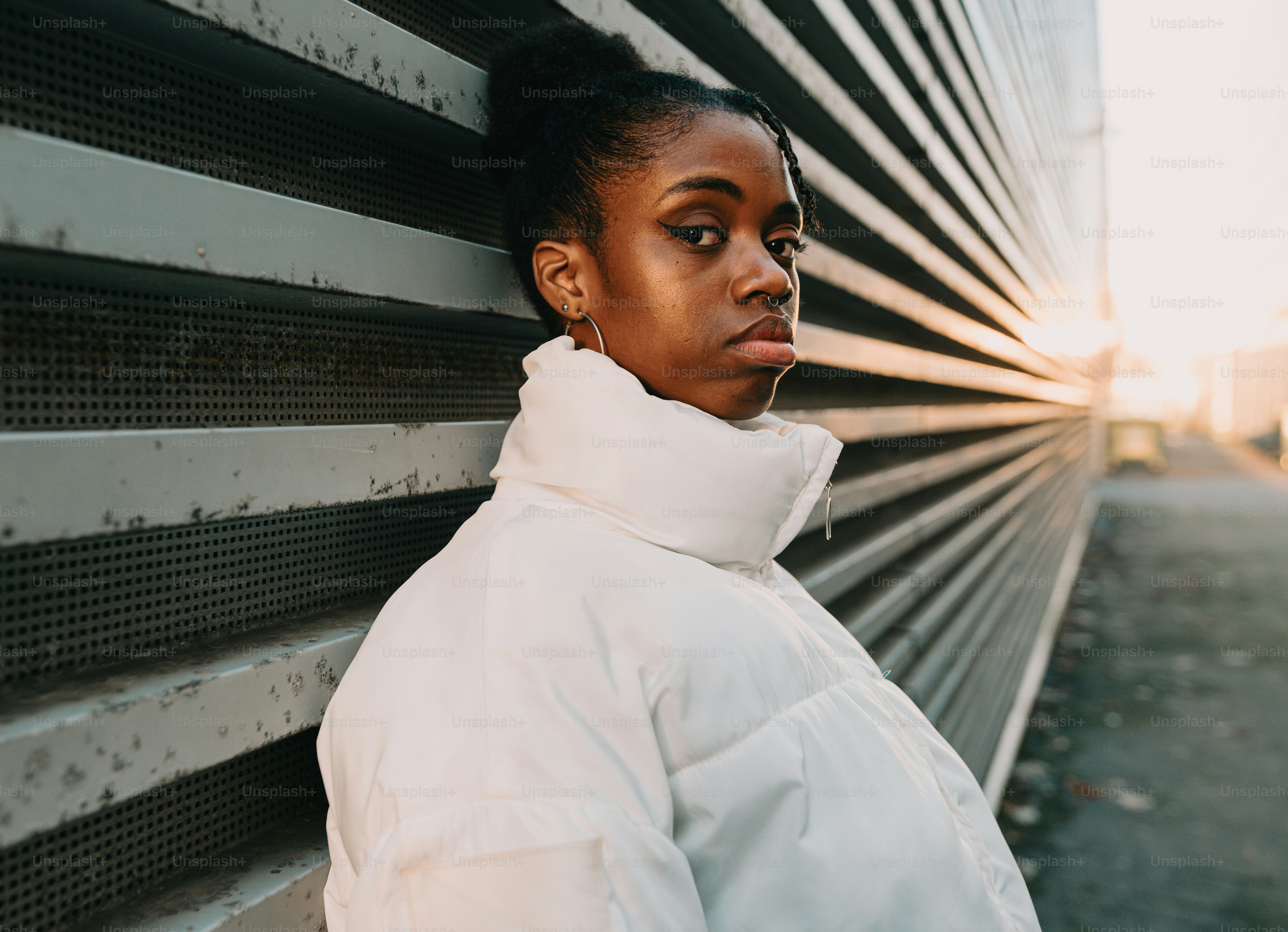 A woman in a white jacket leaning against a wall photo – Fashion Image ...