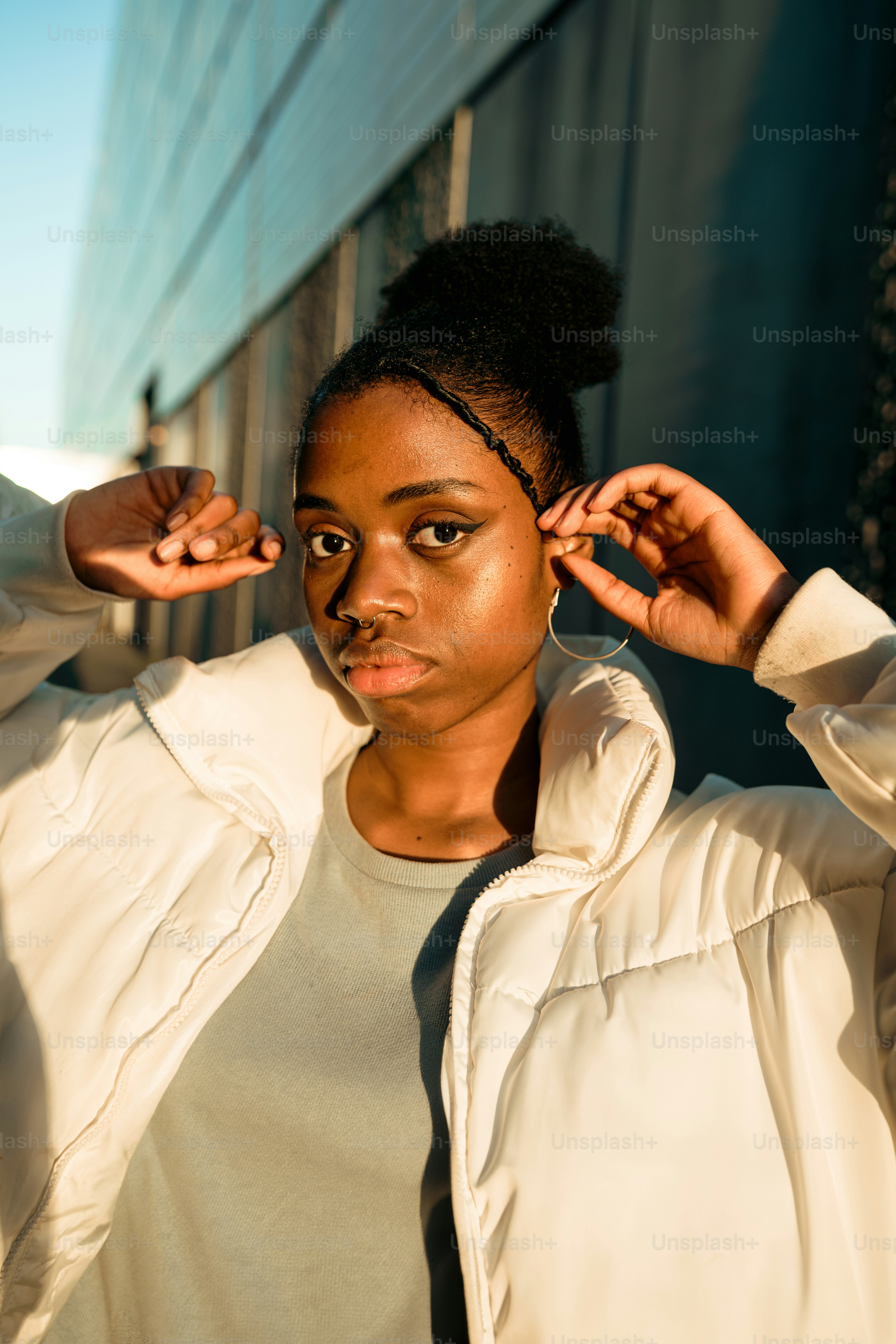 A woman in a white jacket leaning against a wall photo – Portrait Image ...