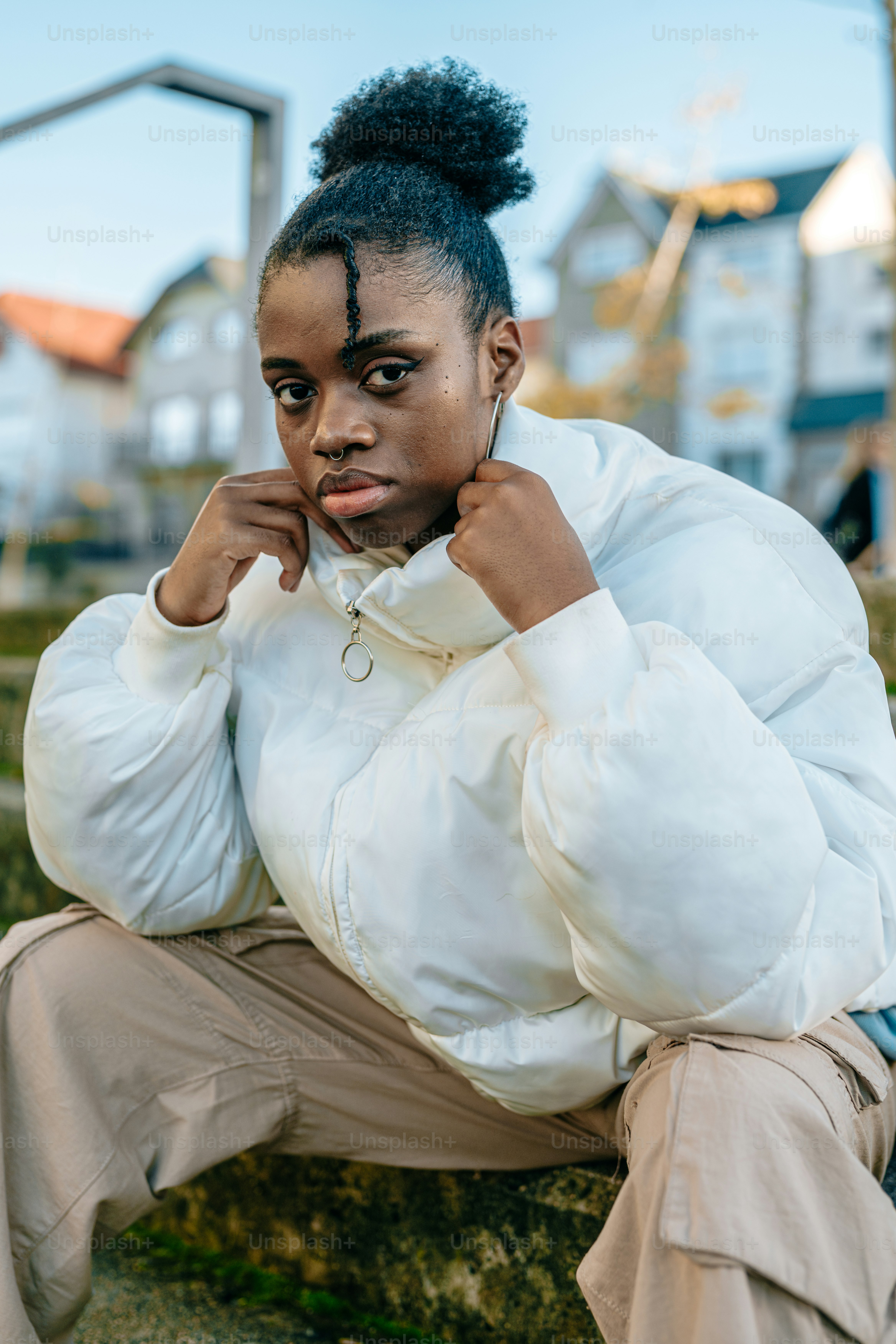 a woman sitting on a rock with her hand on her chin