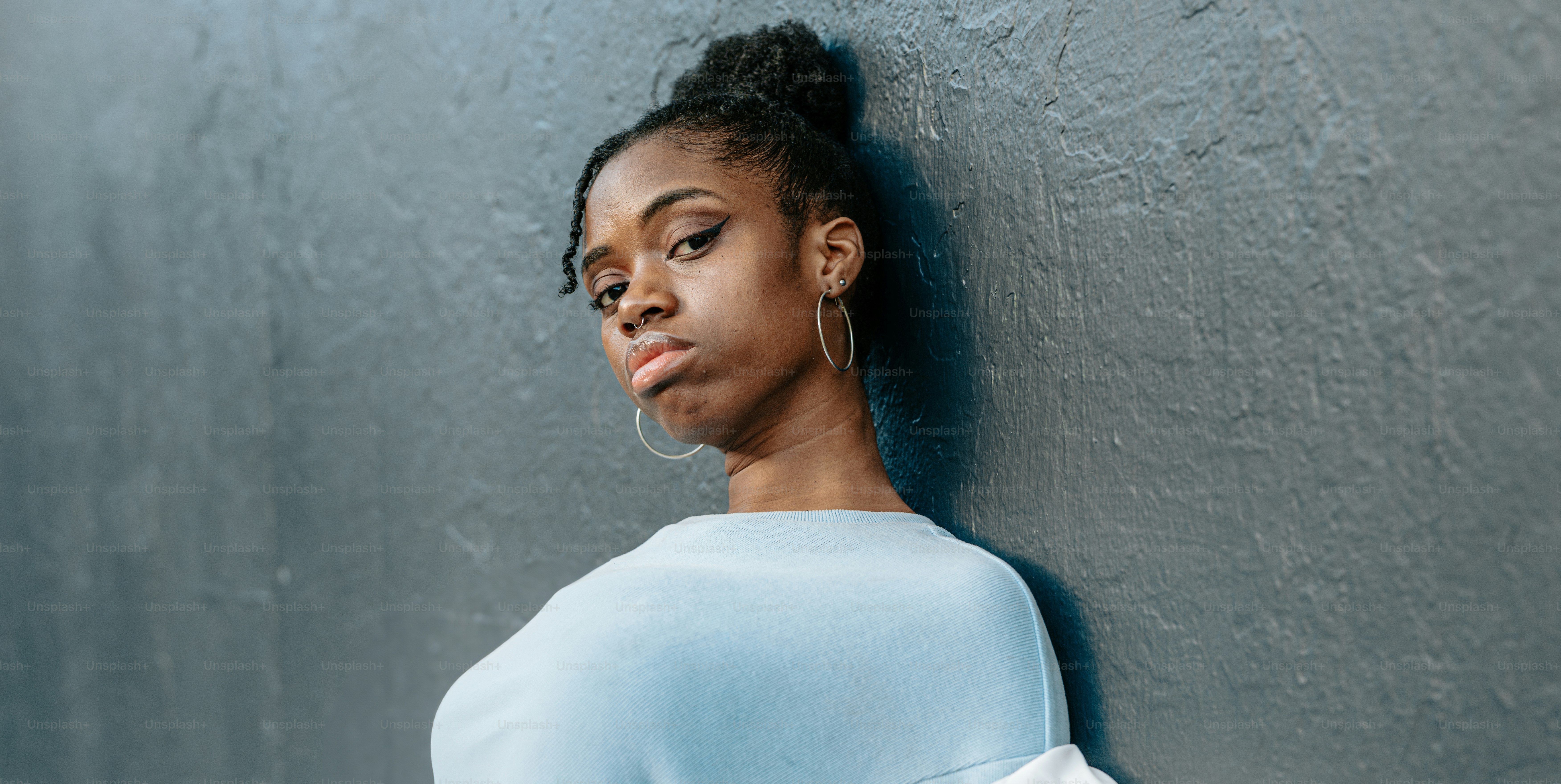 a woman leaning against a gray wall
